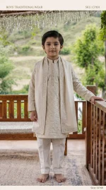 Boy wearing an elegant ivory embroidered Korean silk kurta pajama on a wooden terrace.